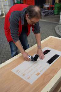 Applying paint to stencil a wooden packing case